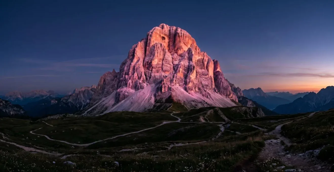 Sommet dolomitique illumine par le phenomene d'enrosadira au coucher du soleil avec teintes roses et orangees sur la roche calcaire
