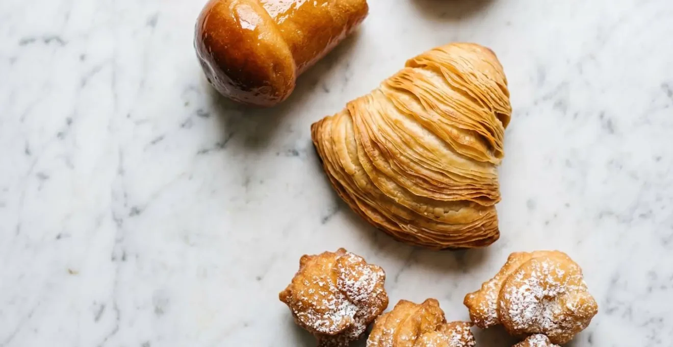 Assortiment de pâtisseries napolitaines traditionnelles avec sfogliatella croustillante et babà au rhum sur table en marbre
